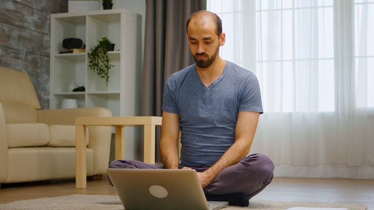 A person meditating in front of a computer